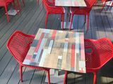 many red chairs and tables on the deck of a restaurant