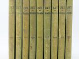 six vieux livres sont alignés sur une surface blanche