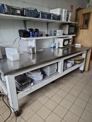 une cuisine avec un plan de travail en métal et des étagères sur lesquelles sont posés de la vaisselle