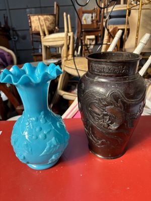 deux vases posés sur une table rouge, avec des chaises en arrière-plan