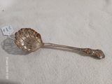 une cuillère en argent avec un manche en forme de feuille, posée sur une table