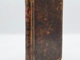 an old book with a brown cover sitting on top of a white surface