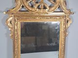 un miroir avec un cadre doré sur un mur blanc