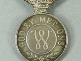 silver medal with a crown and ribbon on a gray surface