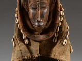 a close up of a wooden mask on a stand