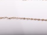 a close up of a gold chain with pearls on it