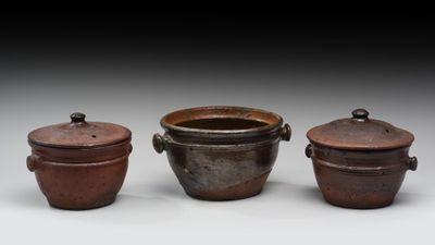trois casseroles marron avec leurs couvercles, posées les unes à côté des autres sur une surface blanche