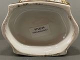 a white and gold vase with a label on it