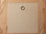 an old picture frame with a ring hanging from it ' s side