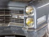 a close up of a silver car with its headlights on