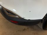 the front bumper of a white car with a dent on it