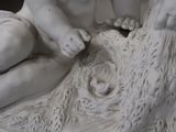 a statue of a baby sitting on top of a tree stump