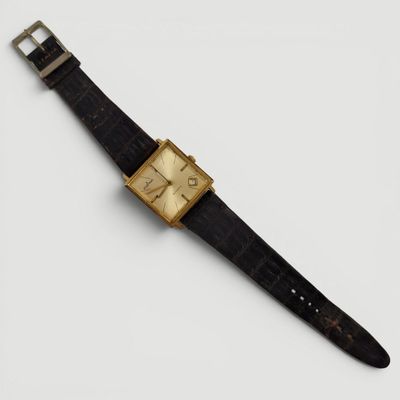 gros plan d'une montre sur une surface blanche avec un bracelet noir