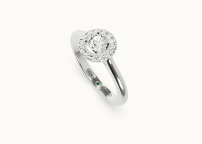 a white gold ring with a diamond and emerald stones