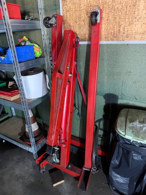 une grande grue rouge dans un garage, à côté d'une poubelle et d'une poubelle