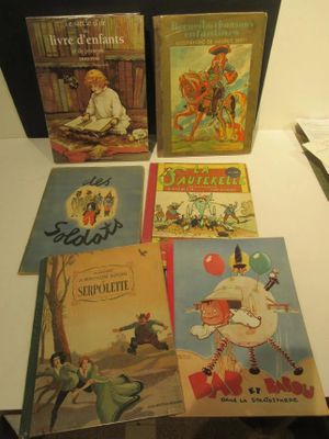 Plusieurs livres pour enfants sont posés sur une table, à côté d'une paire de ciseaux.