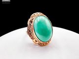 a gold ring with a green stone in the center