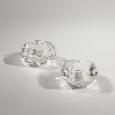 une paire de bougeoirs en verre transparent posés sur une surface blanche