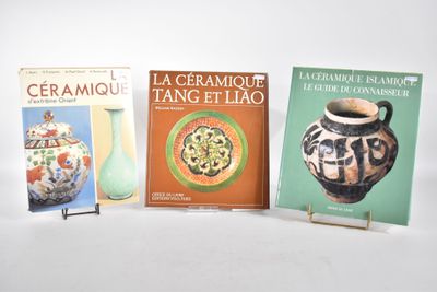 trois livres posés sur une table avec un vase, et un vase posé sur un socle