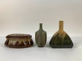 three vases and a box are sitting on a white surface