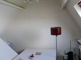 un lit dans un coin d'une pièce où se trouve une lampe rouge