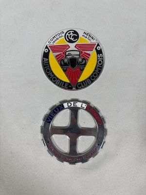 On voit deux insignes sur un fond blanc, ornés d'un motif rouge et jaune.