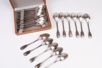 six cuillères et une boîte de couverts posés sur une table