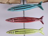 three different colored fish hanging on a metal pole