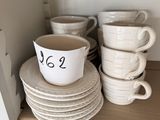 de nombreuses tasses et soucoupes sur une étagère de la cuisine
