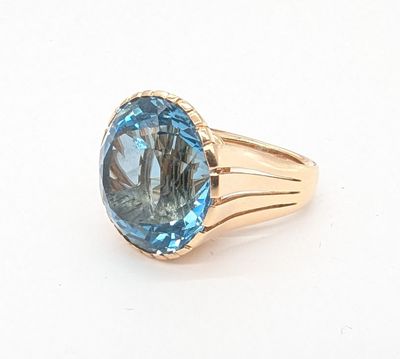 une photo d'une bague sertie d'une topaze bleue posée sur une surface blanche