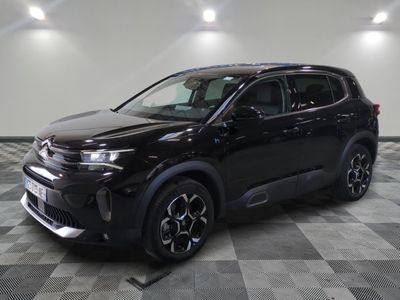 Un SUV noir est garé sur un sol à damier dans un garage.