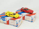 two toy cars sitting on top of boxes on a white surface