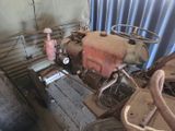 an old tractor sitting in a garage next to other old machinery