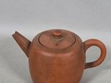 a close up of a small brown teapot on a white surface