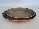 two metal dishes sitting on a white table