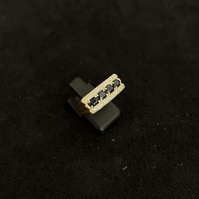 a gold ring with black stones on a black surface