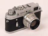 a silver and black camera on a white surface