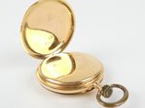 pocket watch on a white surface with a key in the middle