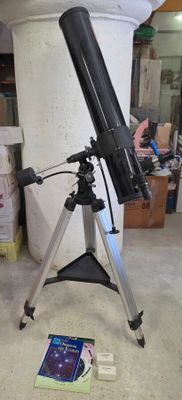 un télescope noir posé sur un trépied, à côté d'un livre