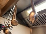 many pots and pans hanging from the ceiling in the kitchen