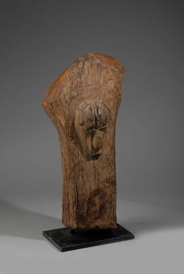 une tête d'homme sculptée dans le bois, posée sur un socle noir