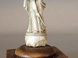 une statue représentant une femme tenant un enfant dans ses bras, posée sur un bloc de bois