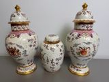 two vases with lids are sitting on a table in front of a wall