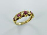 a close up of a gold ring with rubis and diamonds