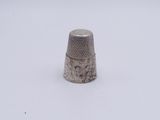 a silver thimble sitting on a white surface