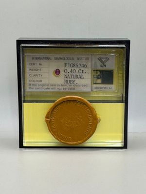a gold medal in a glass case on a white surface