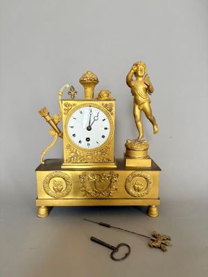 une horloge en or surmontée d'une statue, à côté d'une paire de ciseaux