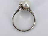 a close up of a white pearl ring on a white surface