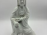 une statue blanche représentant une femme assise sur une table