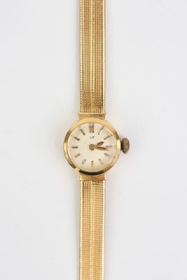 gros plan d'une montre en or sur une surface blanche